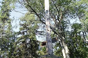 Это крест, сохранившийся с предыдущих времен. В советское время все кресты на Соловках свезли в одно место и сожгли, а этот крест, стоявший на видном месте, да еще под боком у зам. начальника лагеря, который домик в Макарьевской пустыни использовал в качестве резиденции, почему-то остался цел.
